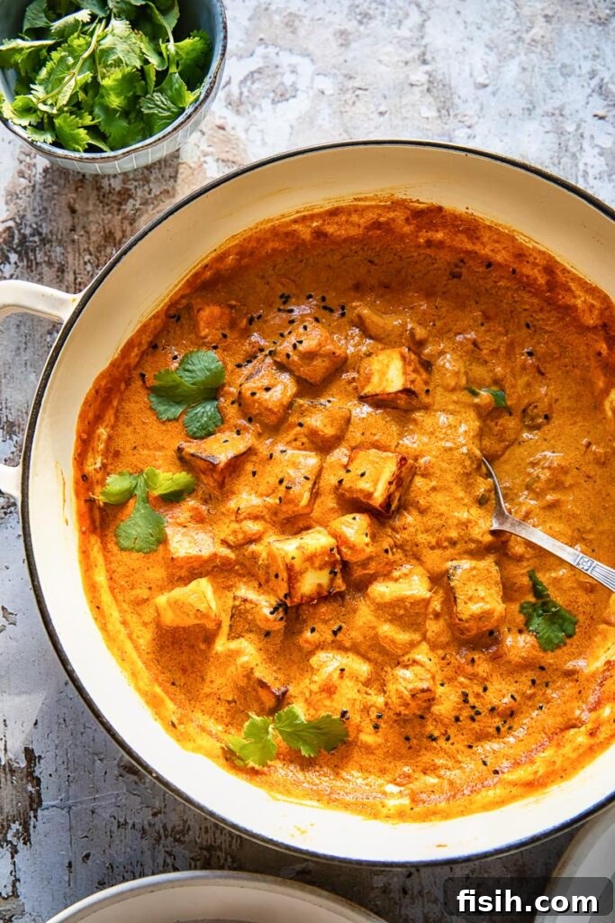 Large pan of vibrant paneer tikka masala garnished with fresh cilantro, ready to serve