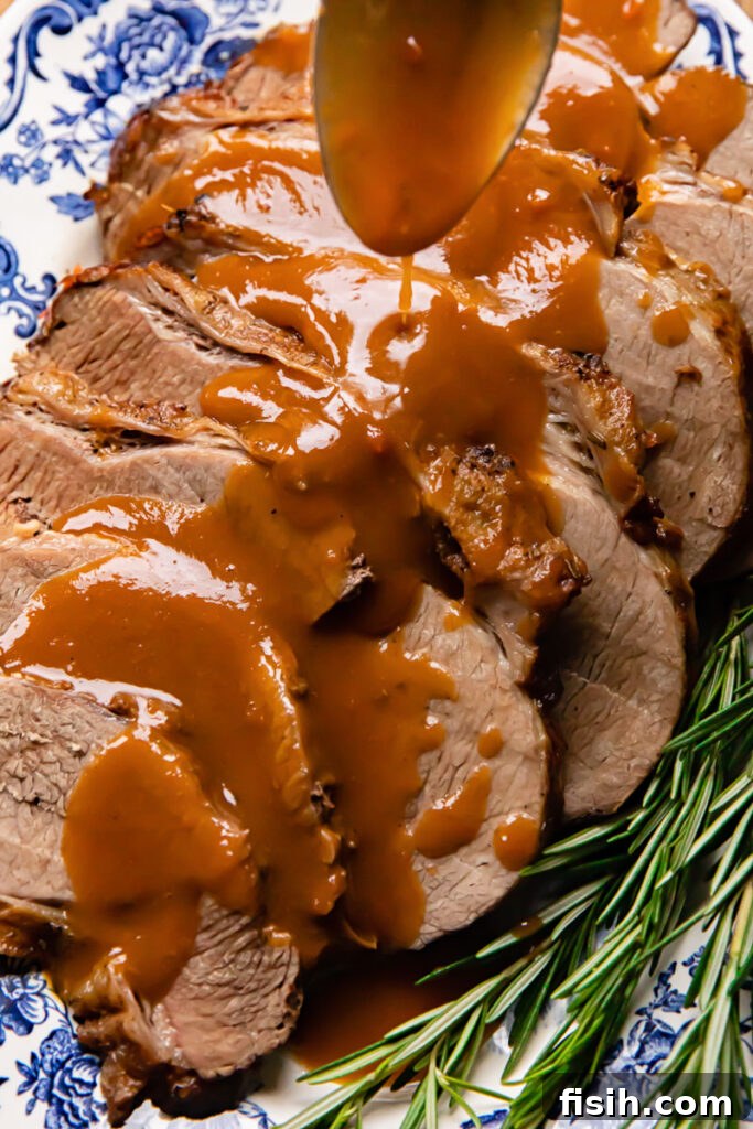 Perfectly Tender Slow Cooker Roast 4 Close up shot of rich, homemade gravy being drizzled generously over tender slices of slow cooker roast beef, creating an appetizing visual.