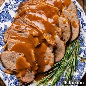 Top down shot of slow cooker roast beef on a plate with gravy and rosemary