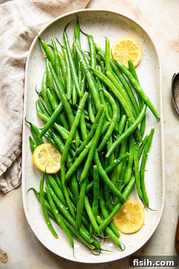 Bright Lemon Butter Green Beans 2 Platter of vibrant lemon butter green beans, garnished with fresh lemon slices and a sprinkle of herbs.
