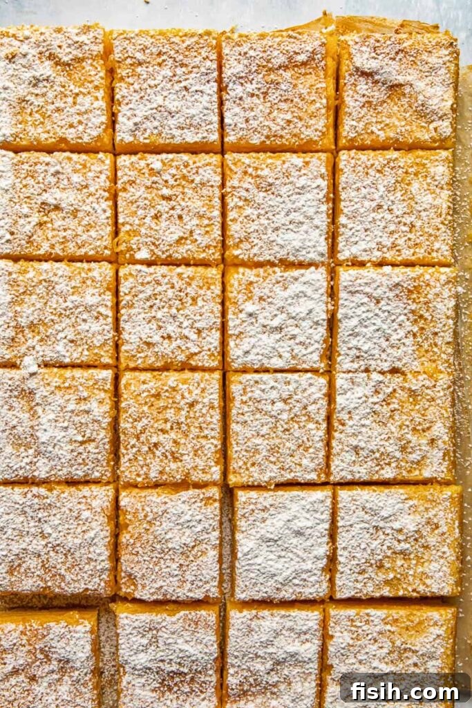 Zesty Lemon Delights 3 Top down shot of lemon bars being cut into pieces on a baking sheet
