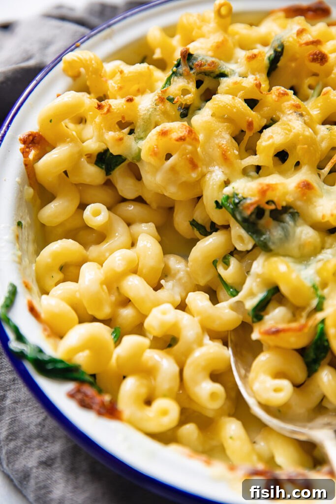 Close-up of a baking dish filled with Brie Mac and Cheese, showing the rich, gooey cheese bubbling and stretching.