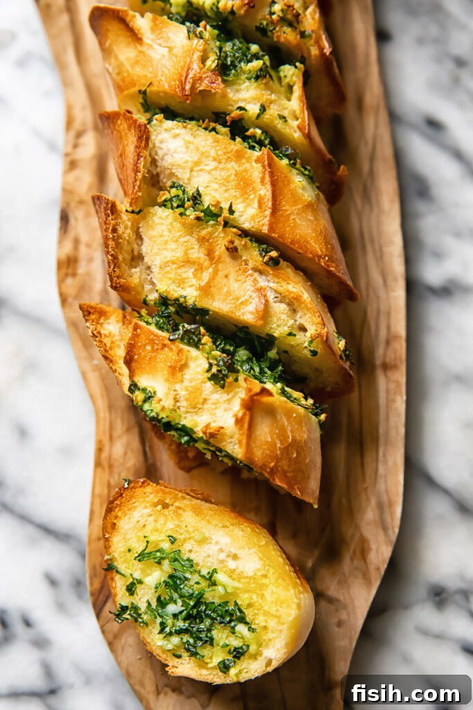 Top down shot of perfectly golden slices of cheesy garlic bread, arranged artfully on a wooden cutting board, garnished with fresh parsley.
