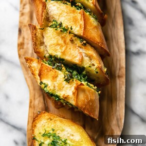 Top down shot of slices of garlic bread layered next to each other on a cutting board