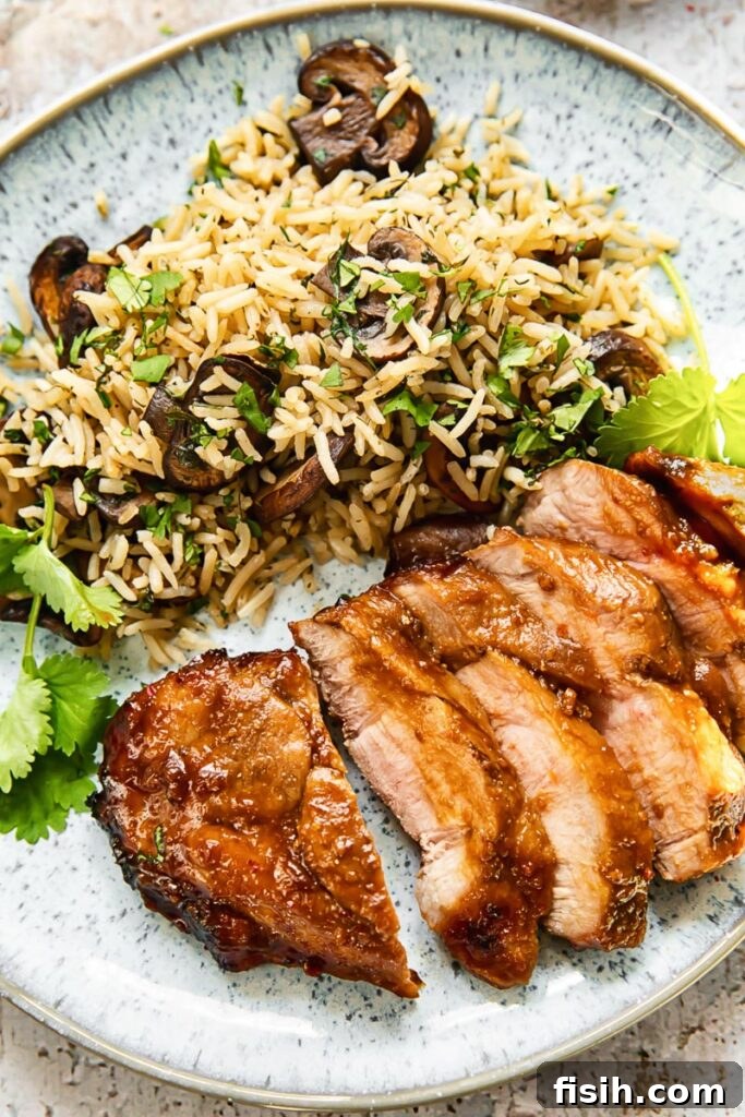 Top down view of boneless pork chop slices on a plate with herbed mushroom rice