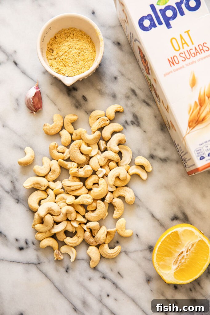 Creamy Vegan Alfredo Sauce 4 Cashews, lemon and oat milk carton on a marble surface
