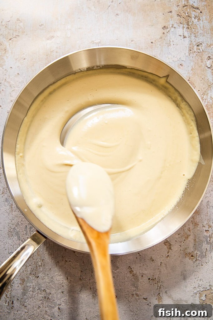 Creamy Vegan Alfredo Sauce 5 Bowl of vegan Alfredo sauce with a spoon pulled away showing creamy consistency
