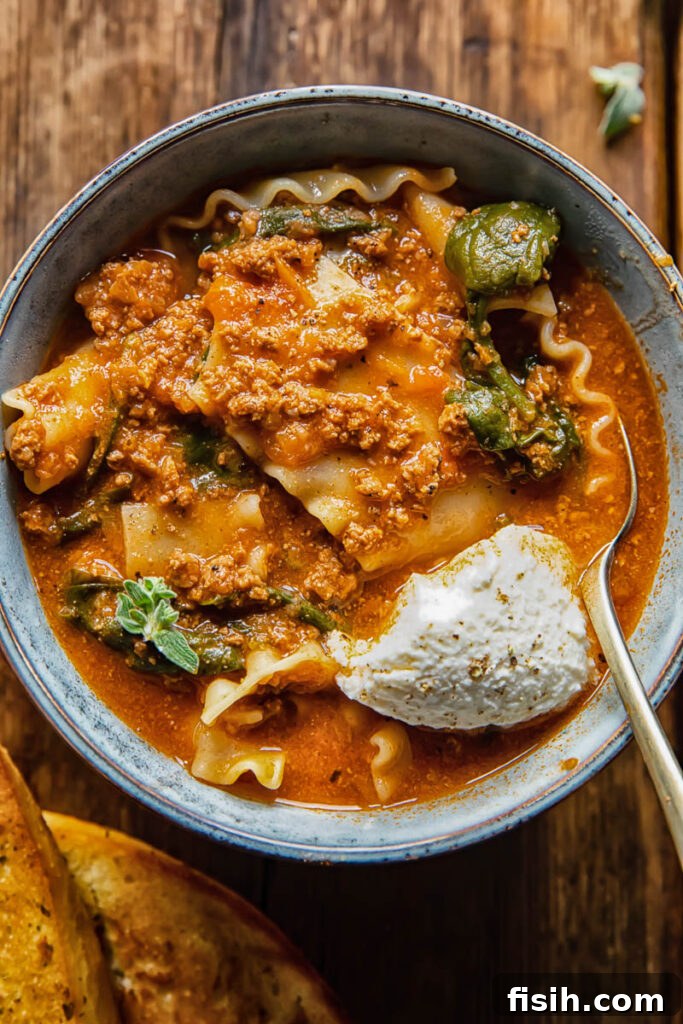 bowl of lasagna soup with dollop of sour cream and a spoon