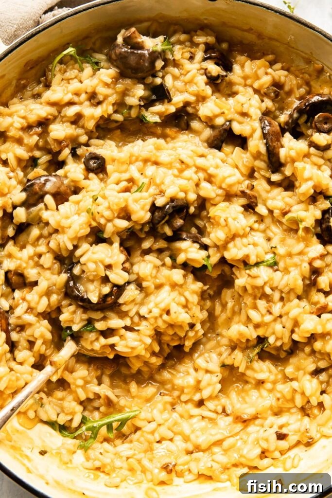 Earthy Roasted Mushroom Risotto 3 Close-up of creamy mushroom risotto in a bowl with a silver spoon, showing the rich texture.