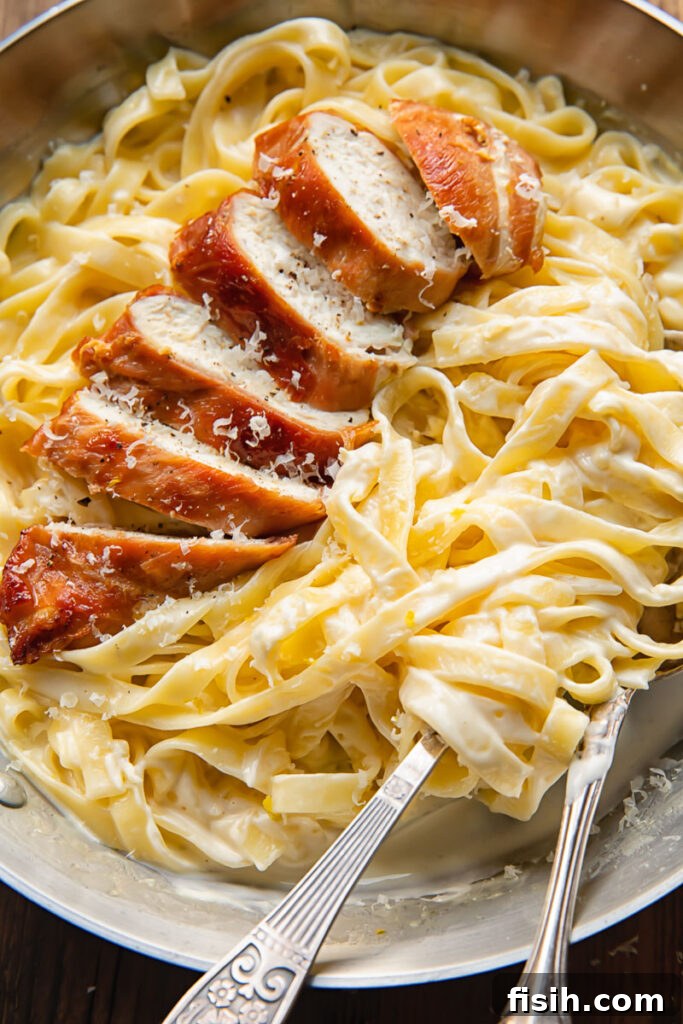 Top down shot of prosciutto wrapped chicken alfredo with creamy fettucine in a bowl with a fork