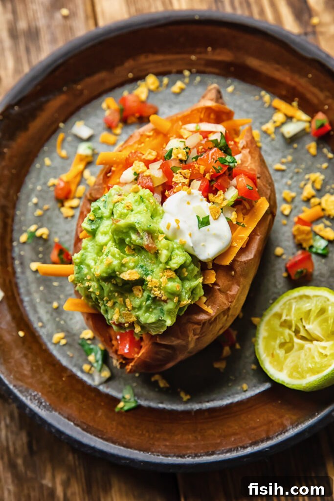 Top down shot of a baked sweet potato on a plate topped with vibrant pico de gallo and creamy guacamole, ready to eat