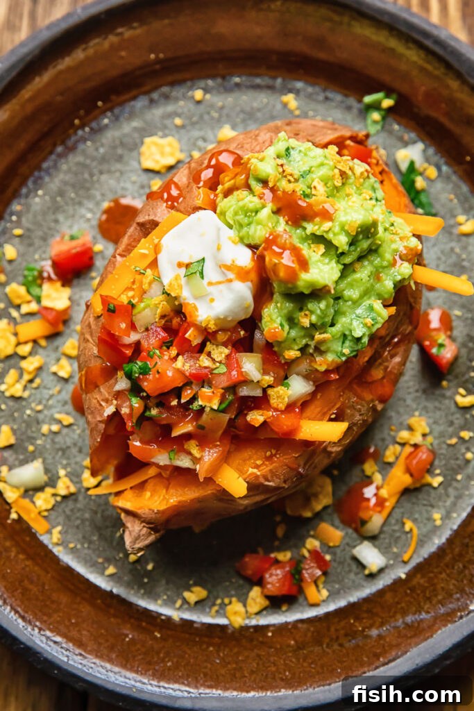 Top down view of a baked potato generously topped with creamy sour cream, vibrant green guacamole, and fresh red salsa.