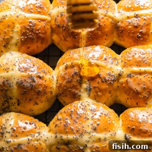 Sunshine Lemon Poppy Seed Hot Cross Buns 7 Honey being drizzled on top of a hot cross bun