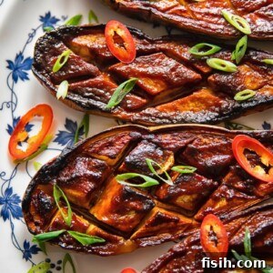 Four pieces of glazed eggplant on a plate, close up view.