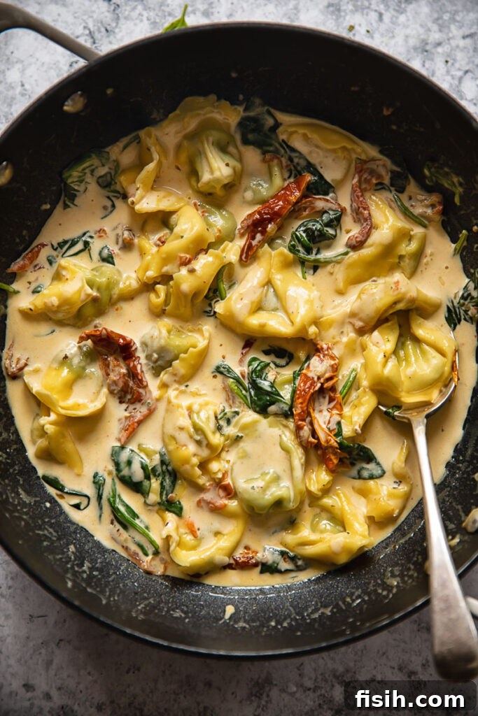 top down of a pan with tuscan tortellini sauce and a spoon