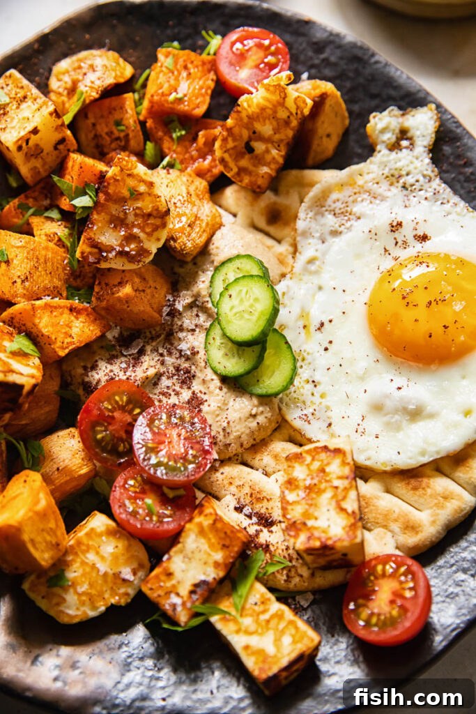 Close-up view of the sweet potato hash, showcasing the crispy edges of the sweet potatoes, the golden-brown halloumi, and the luscious baba ganoush spread.