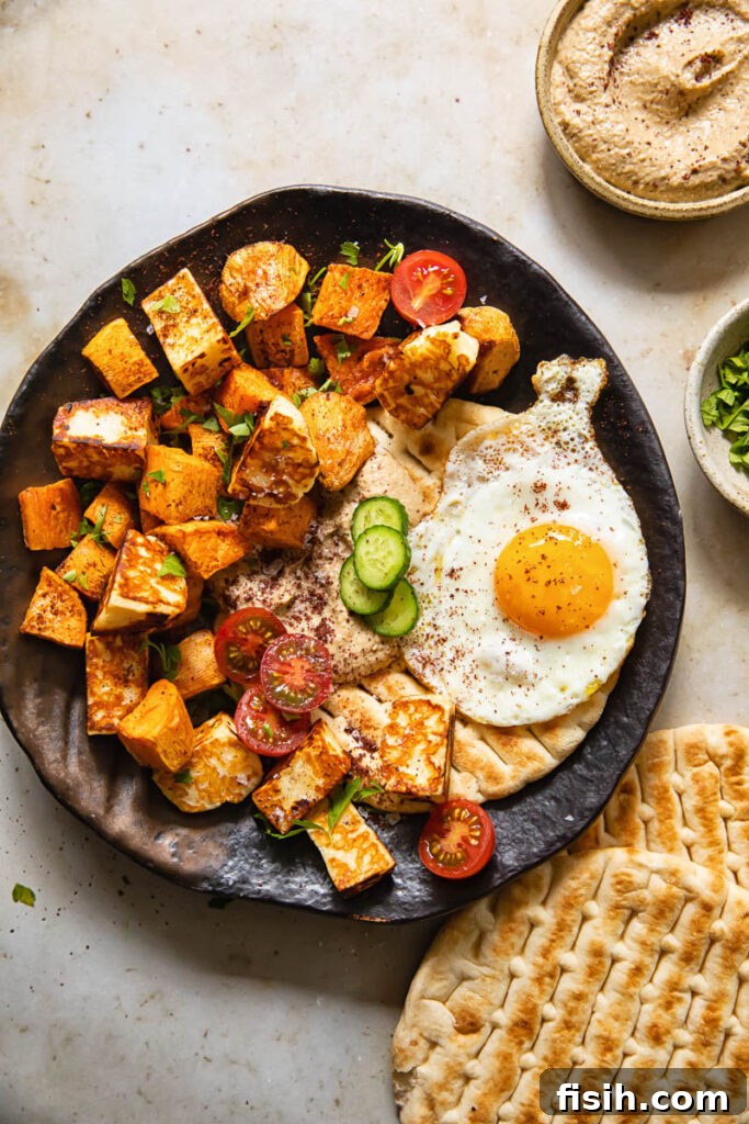A vibrant plate of sweet potato hash with baba ganoush, golden halloumi, a fried egg, and a side of flatbread, ready to be enjoyed.