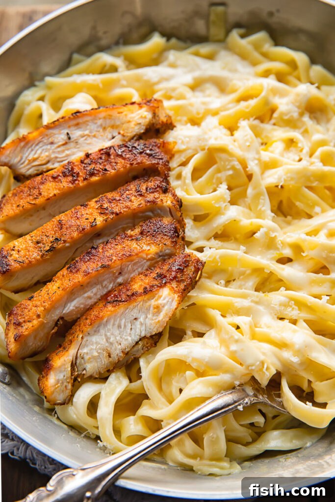 Bold Blackened Chicken Alfredo 2 Top down shot of tagliatelle in alfredo sauce topped with blacken chicken strips in a bowl