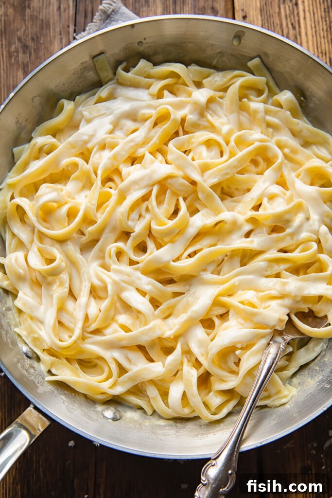 Bold Blackened Chicken Alfredo 3 Top down shot of fettucine pasta in a pan with creamy alfredo sauce