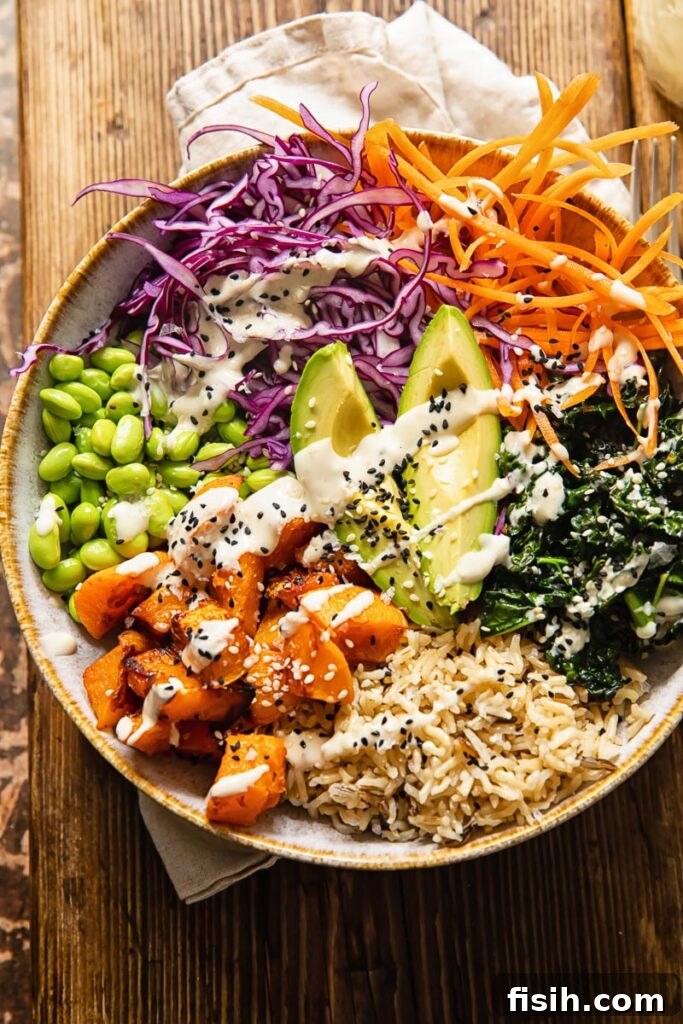 A vibrant Buddha bowl artfully arranged on a rustic wooden table, with lemon tahini dressing drizzled over the top.