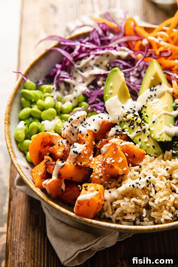 Side view of a vibrant Buddha bowl, showcasing layers of roasted vegetables, fresh greens, and grains, ready to be enjoyed.