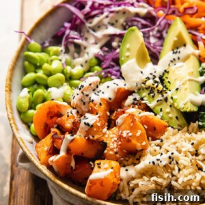 Side view of a colorful vegan Buddha bowl with roasted butternut squash, avocado, and fresh greens, drizzled with lemon tahini dressing.