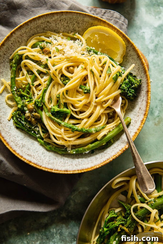 A close-up, top-down view of a bowl of Lemon Garlic Pasta, with a fork twirled into the noodles, showcasing the fresh vegetables and light sauce.
