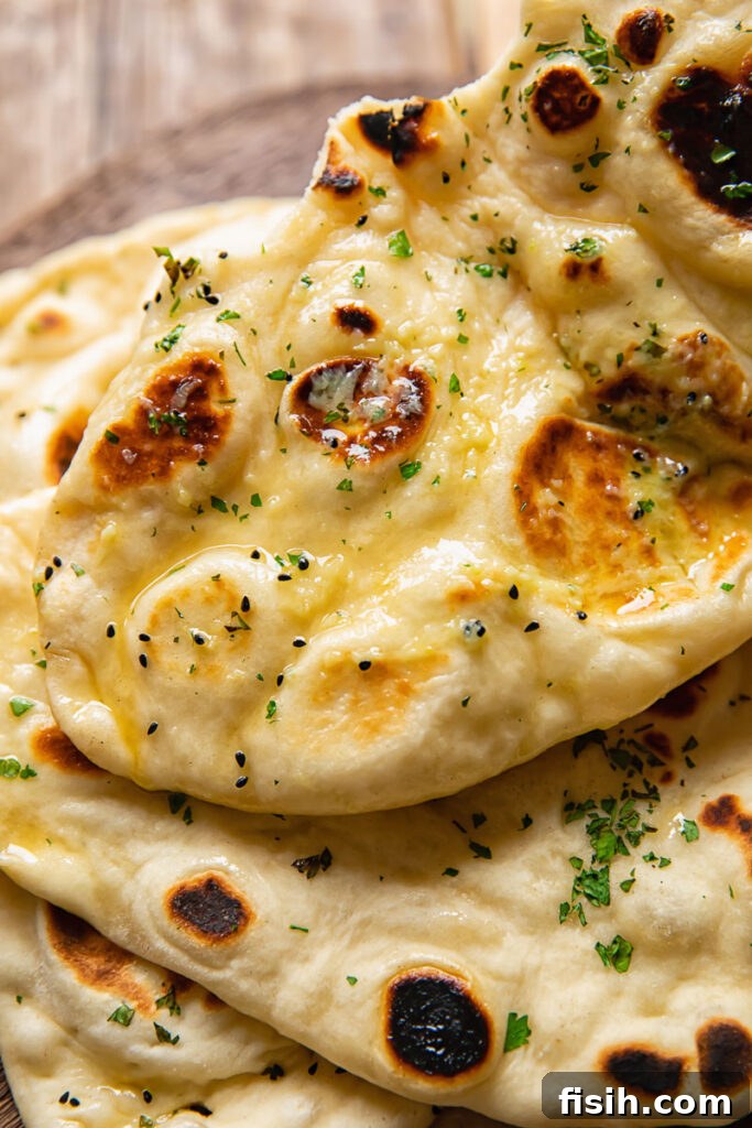 Top down shot of naan topped with herby garlic butter on a cutting board, garnished with fresh cilantro.