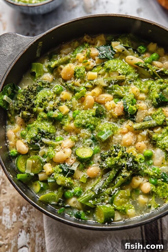 A large pot of vibrant vegetarian minestrone soup sits on a rustic wooden background, ready to be served.