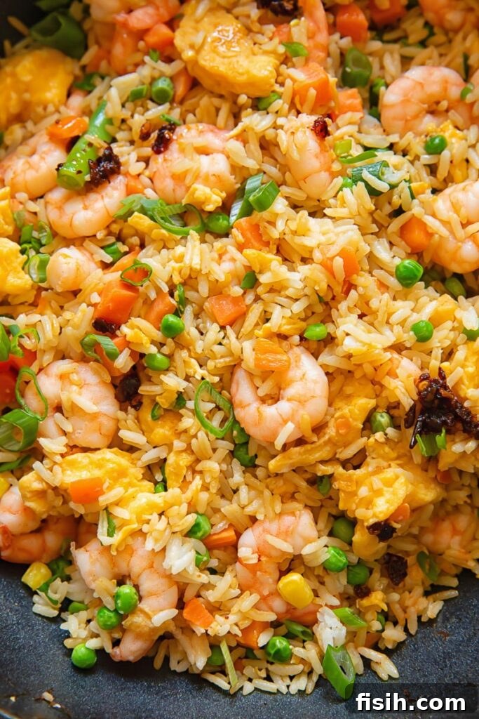 Close up shot of egg fried rice with shrimp carrots and peas, topped with green onions