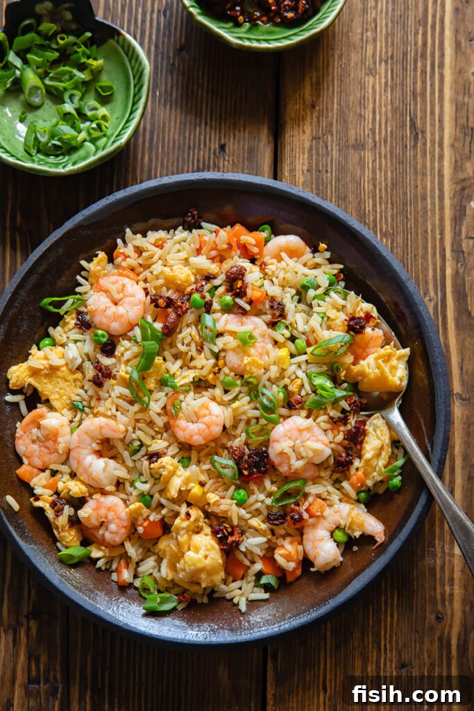 Top down shot of shrimp fried rice on a plate with veg and chilli crisp