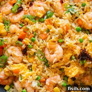 Close up shot of egg fried rice with shrimp carrots and peas, topped with green onions