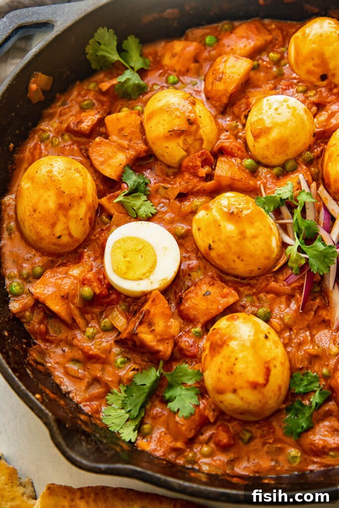 Close up of egg curry in a frying pan with eggs on top