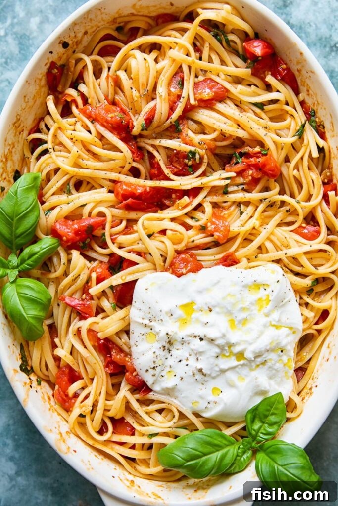 A beautifully presented serving dish of roasted cherry tomato pasta, generously topped with creamy burrata, captured from an overhead perspective, inviting diners to indulge.