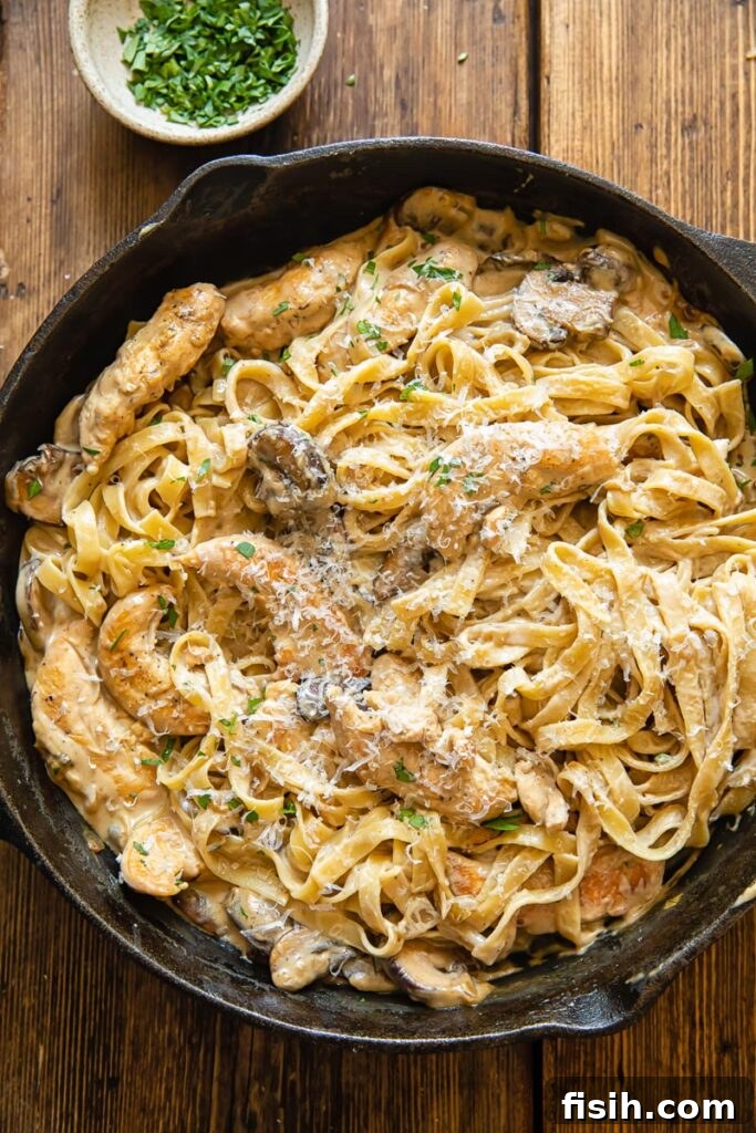 Rich Chicken Marsala Fettuccine 3 Top down shot of chicken marsala fettuccine in a pan next to a bowl of parsley
