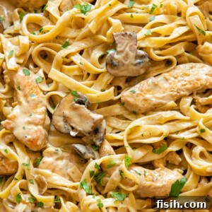 Close up shot of fettuccine pasta with mushrooms and chicken strips in a creamy marsala sauce
