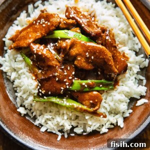 Top down shot of mongolian beef stir fry on a bed rice on a plate with chopsticks