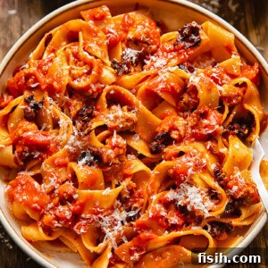 Close up shot of sausage ragu in a bowl with chilli crisp and Parmesan