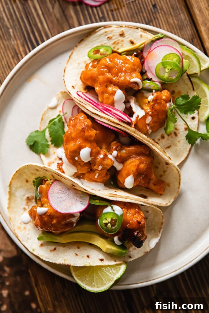 Buffalo cauliflower tacos folded and leaning together on a plate