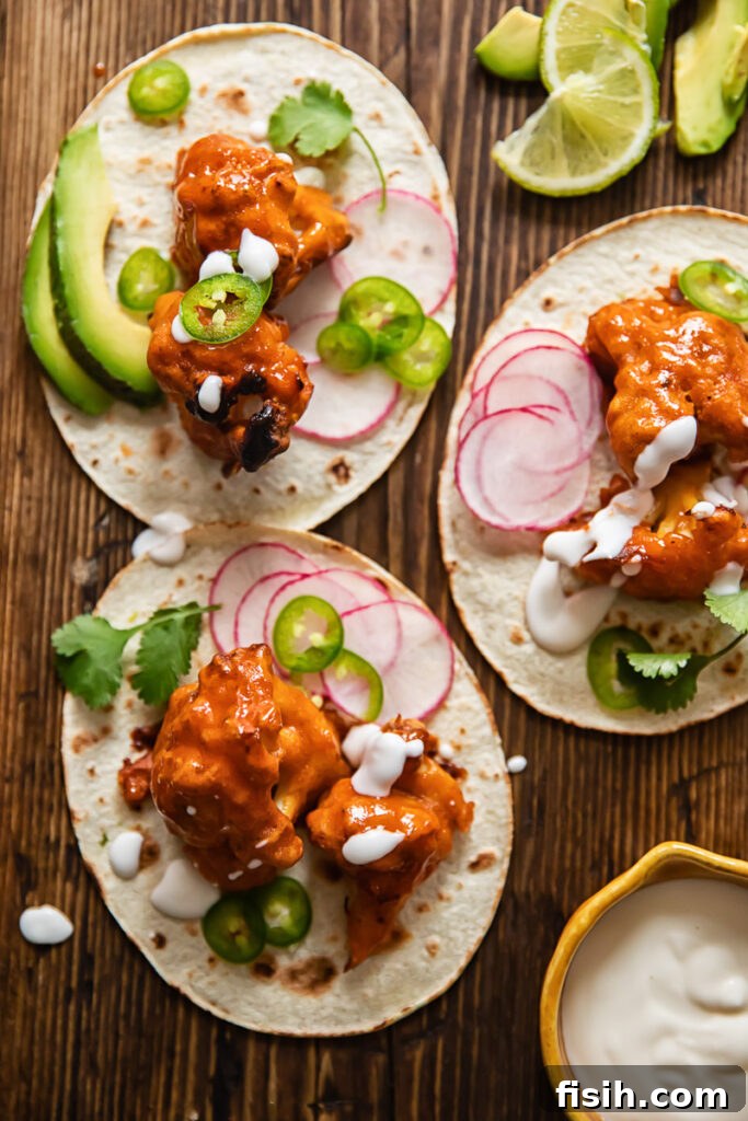 Buffalo cauliflower tacos with toppings on a tabletop