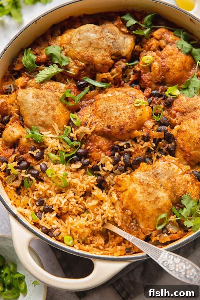 Top down shot of mexican chicken rice in a pan topped with black beans and cilantro