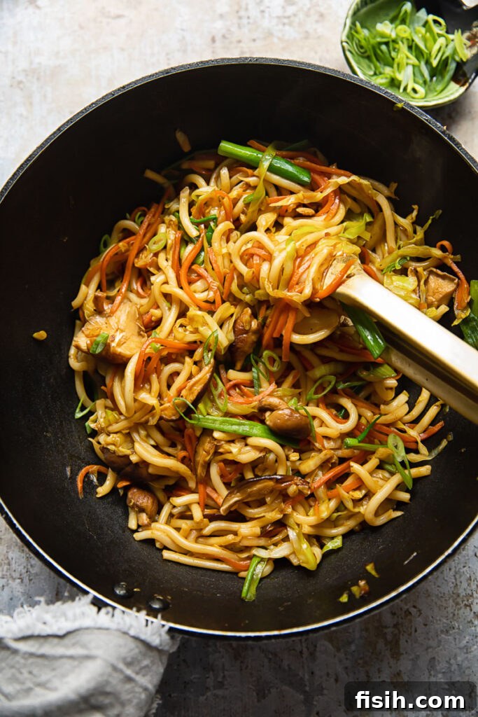Vegetarian Yaki Udon Stir-Fry 2 Top down view of a wok with vibrant vegetarian yaki udon noodles being expertly stirred, showcasing colorful vegetables and glistening sauce.