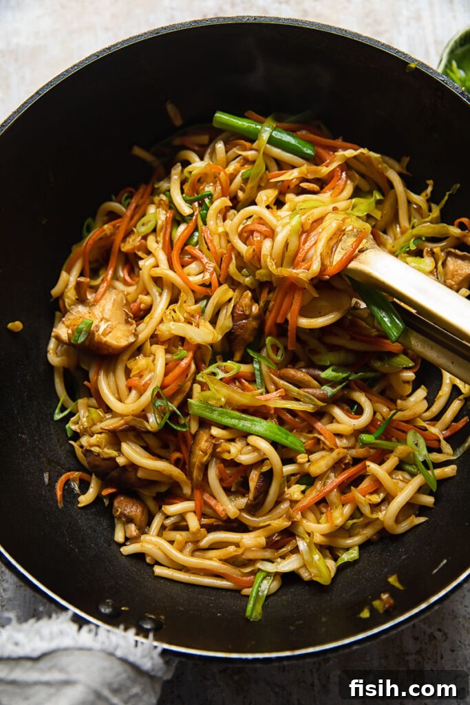 Vegetarian Yaki Udon Stir-Fry 5 Overhead shot of vegetarian yaki udon in a wok, being stirred with chopsticks, ready to be served.