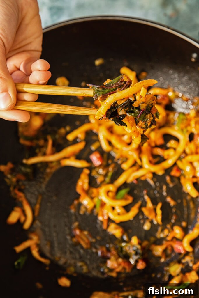 Kimchi Noodles in Minutes 4 A close-up shot of kimchi noodles being lifted with chopsticks, highlighting the texture and glistening sauce