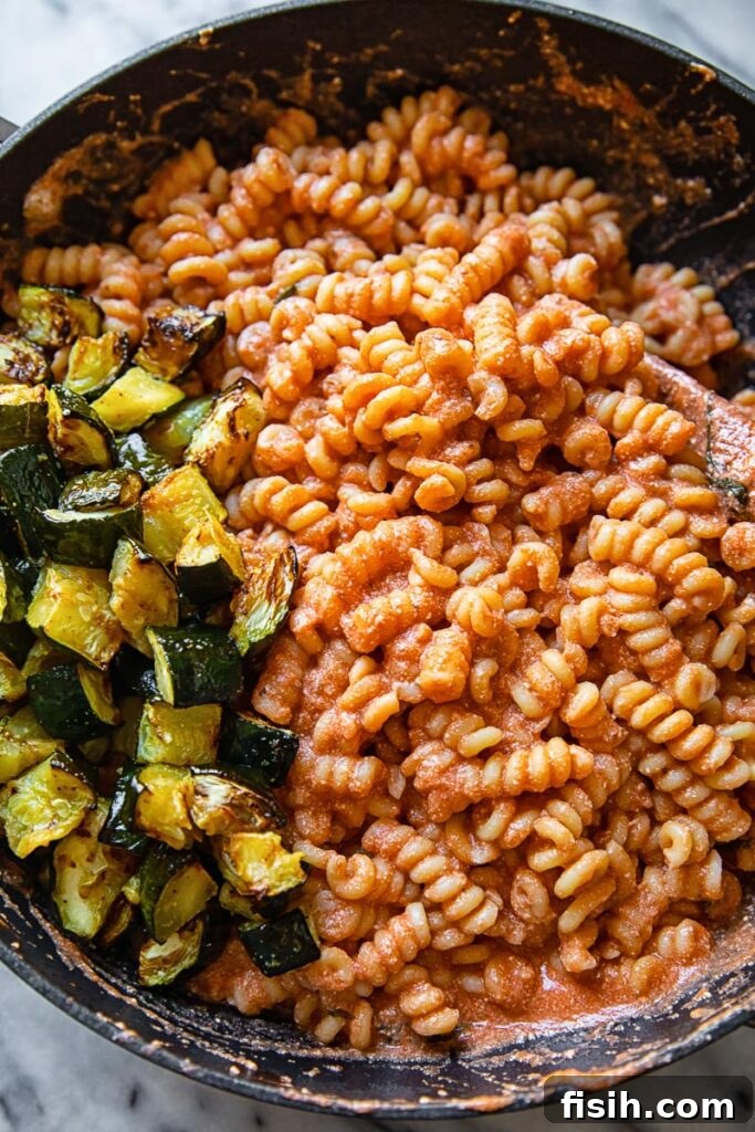 Pan with pasta covered in sauce and portion of fried zucchini