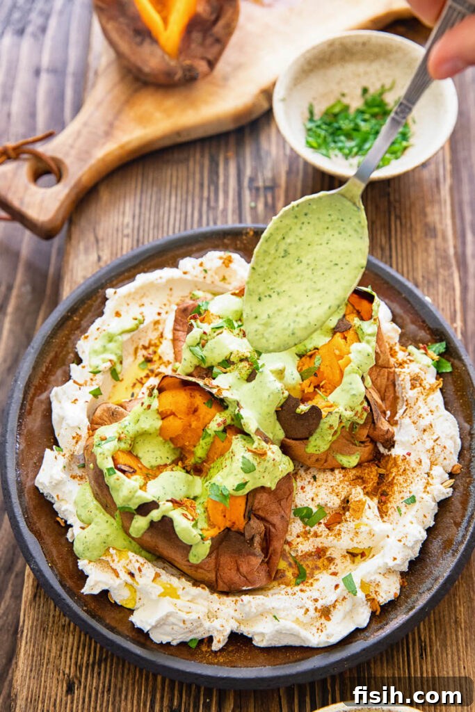 spoon adding tahini sauce to roasted sweet potato