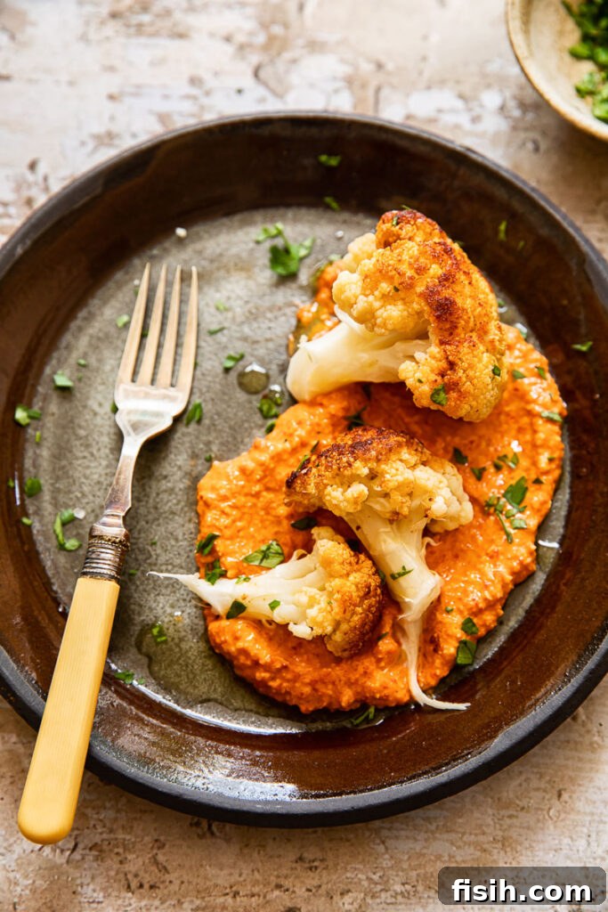 Top down of a plate of romesco sauce with cauliflower florets and fork