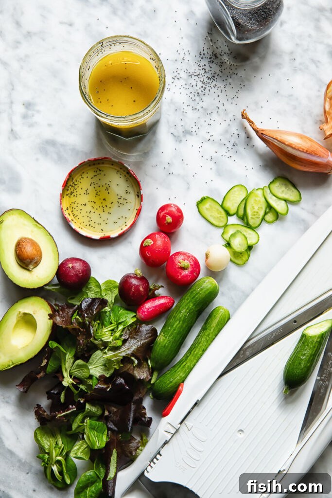 Top down shot of a jar of poppyseed salad dressing next to radish and cucumber slices and half an avocado