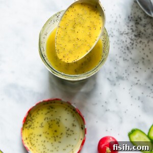 Top down shot of a spoon scooping poppyseed salad dressing out of a glass jar