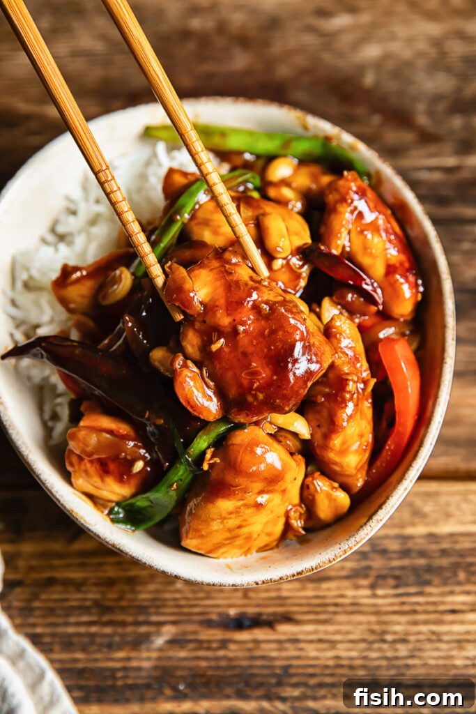 Close up shot of piece of chicken being picked up with chopsticks from szechuan stir fry
